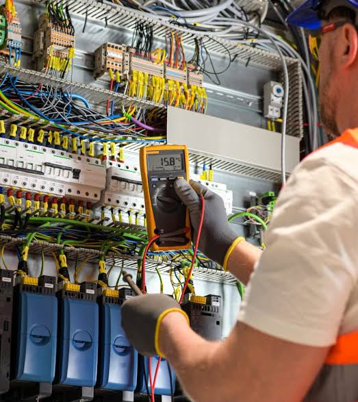 Electrician testing voltage on a control panel